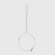 Silver hand chain bracelet with round-cut and teardrop-cut cubic zirconia detailing, shown on a plain background.