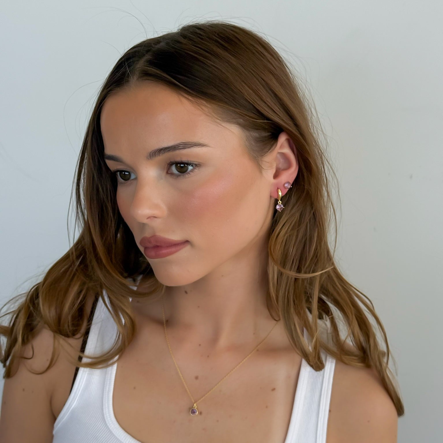 Woman wearing a white tank top against a plain background