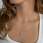 Necklace with a pendant worn by a person with light skin and brown hair.