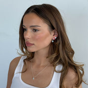 Woman wearing a necklace and earrings against a light background