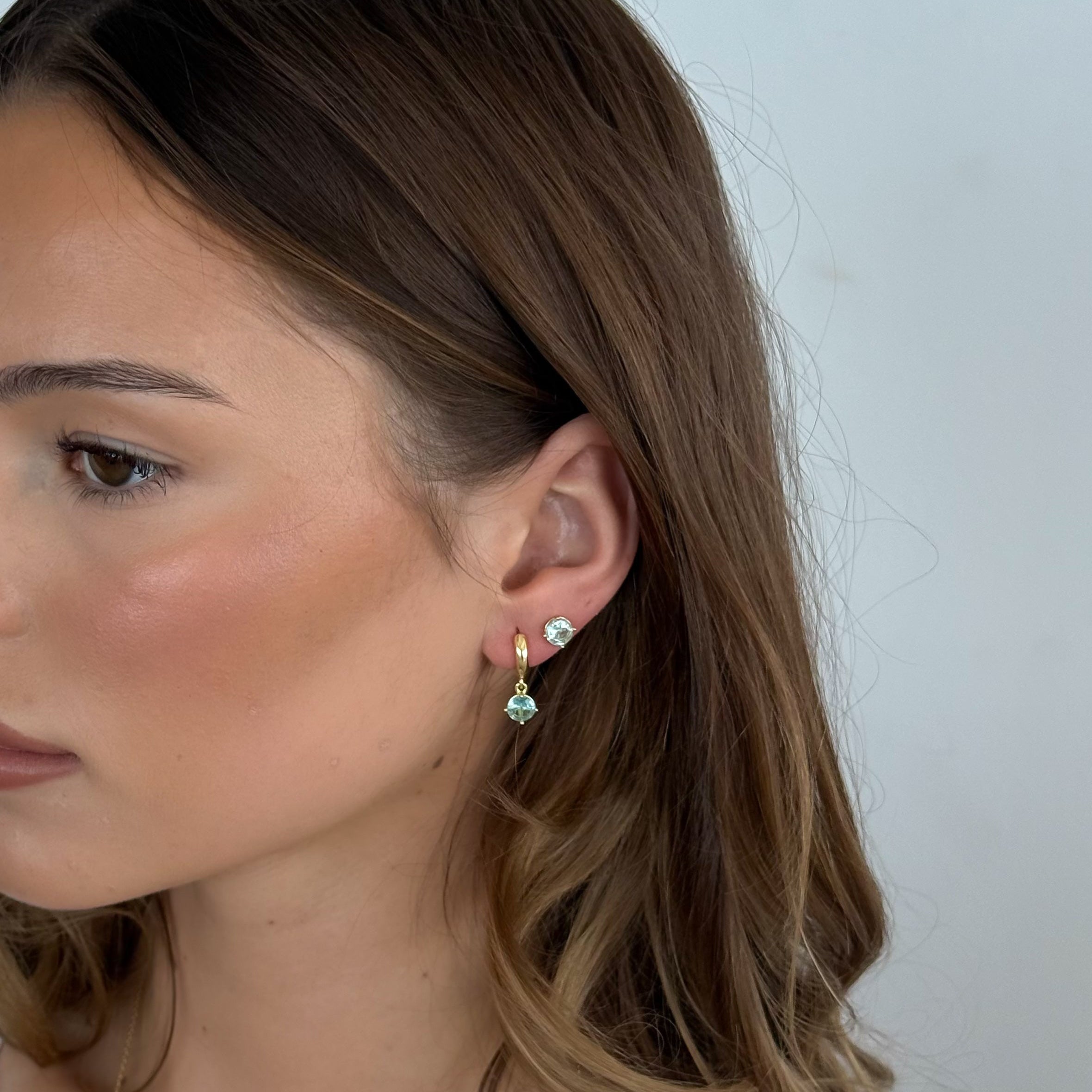Close-up of a woman wearing earrings with a plain background