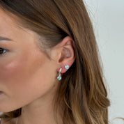 Close-up of a woman wearing earrings with a plain background