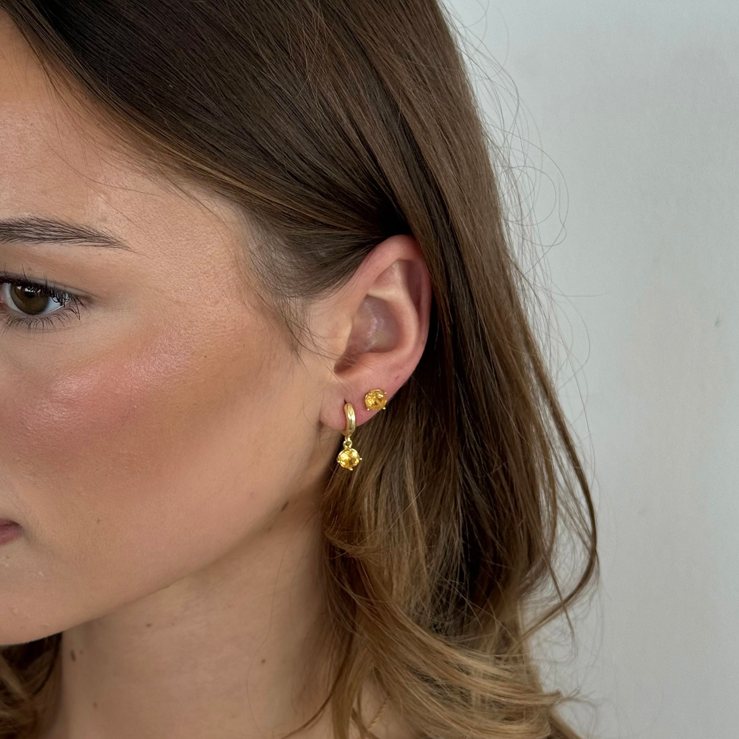 Close-up of a woman wearing gold earrings with a plain background