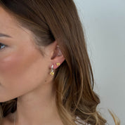 Close-up of a woman wearing gold earrings with a plain background
