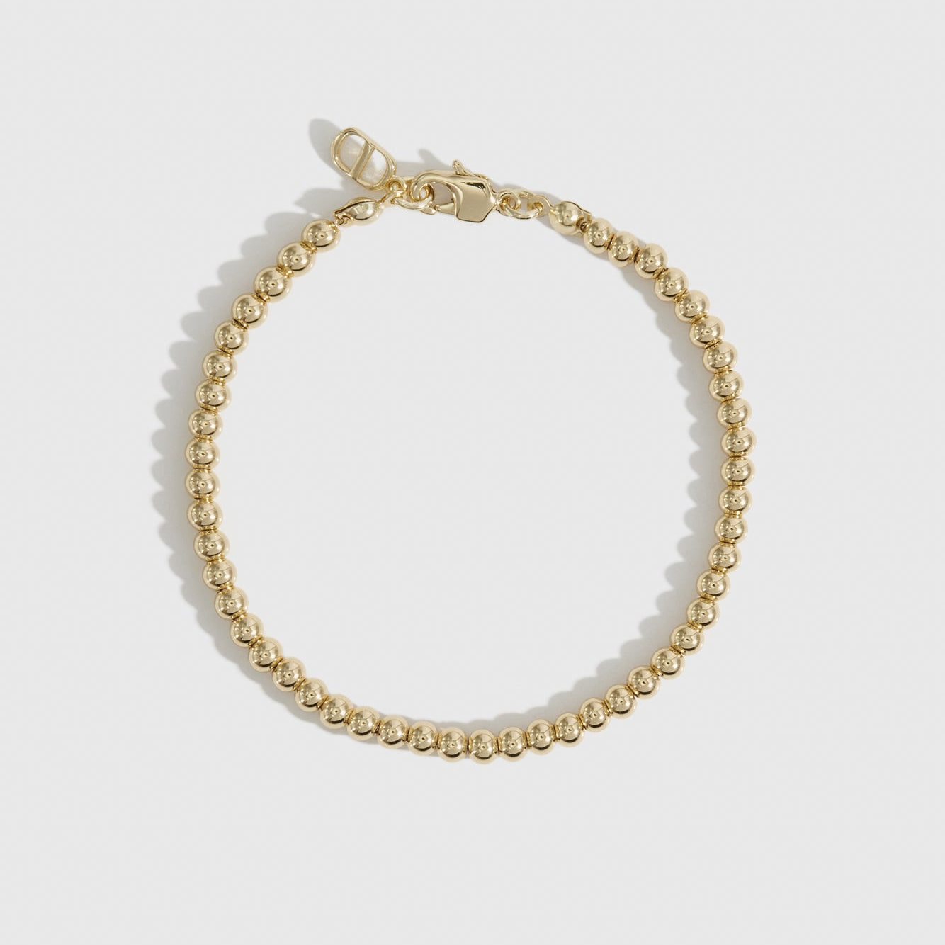 14k gold plated small beaded bracelet, shown on a plain background.