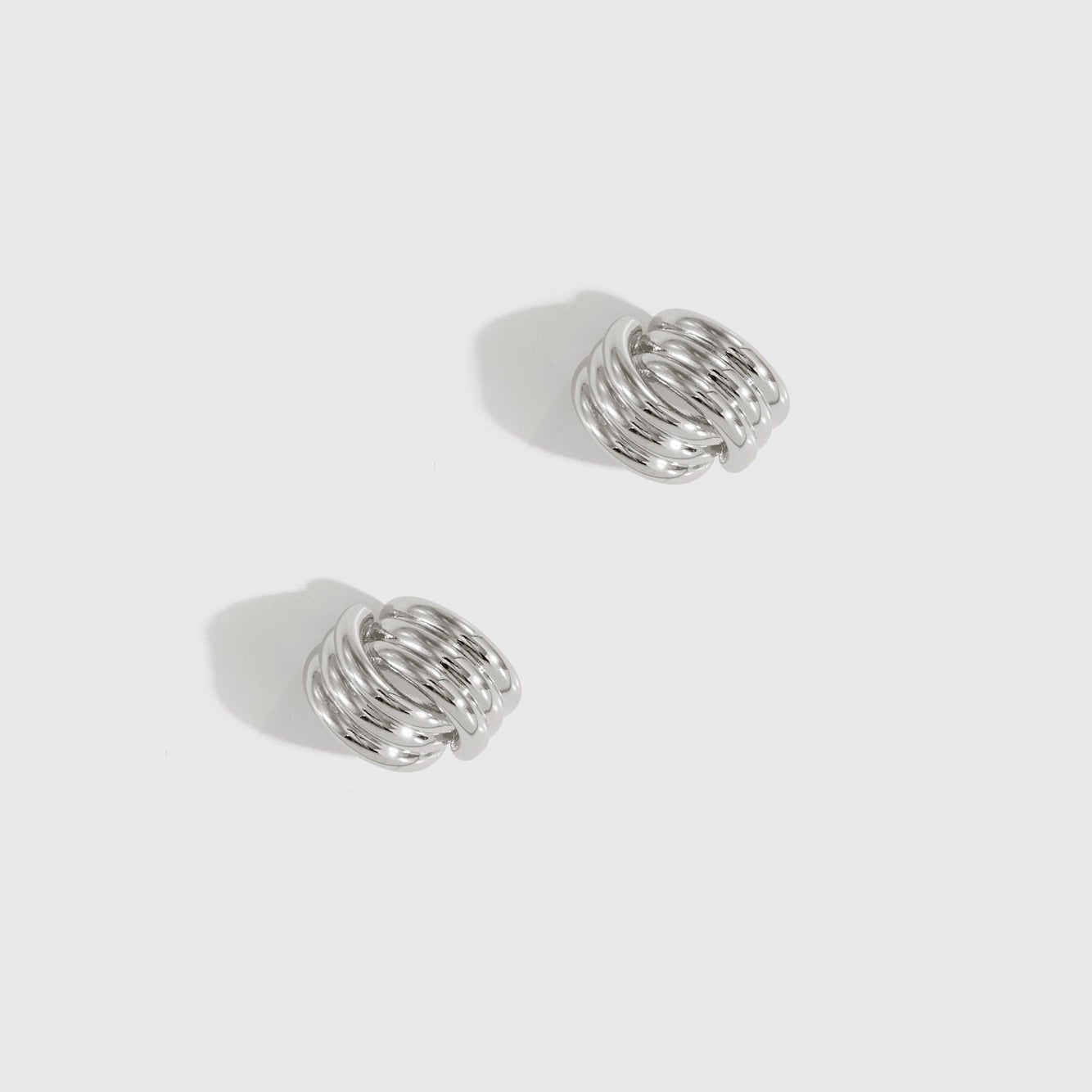 Silver plated intertwined ribbed stud earrings, shown on a plain background.