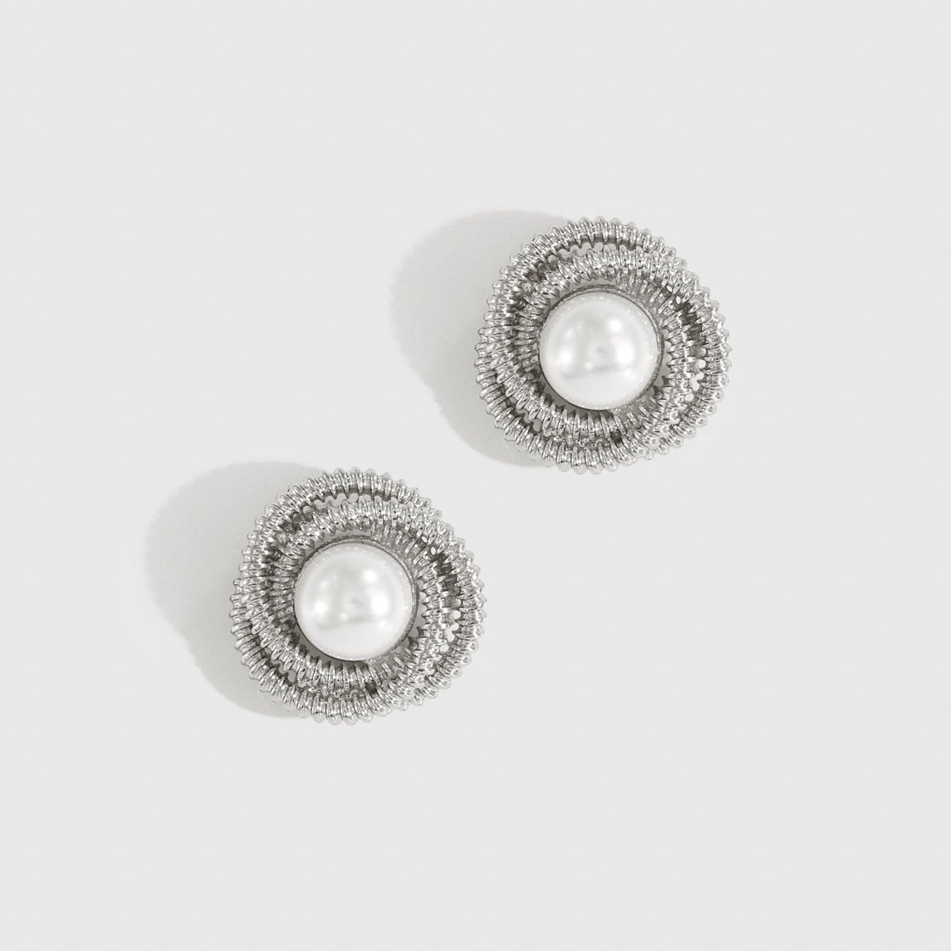 Silver plated mini 90's pearl stud earrings with a pearl, shown on a plain background.