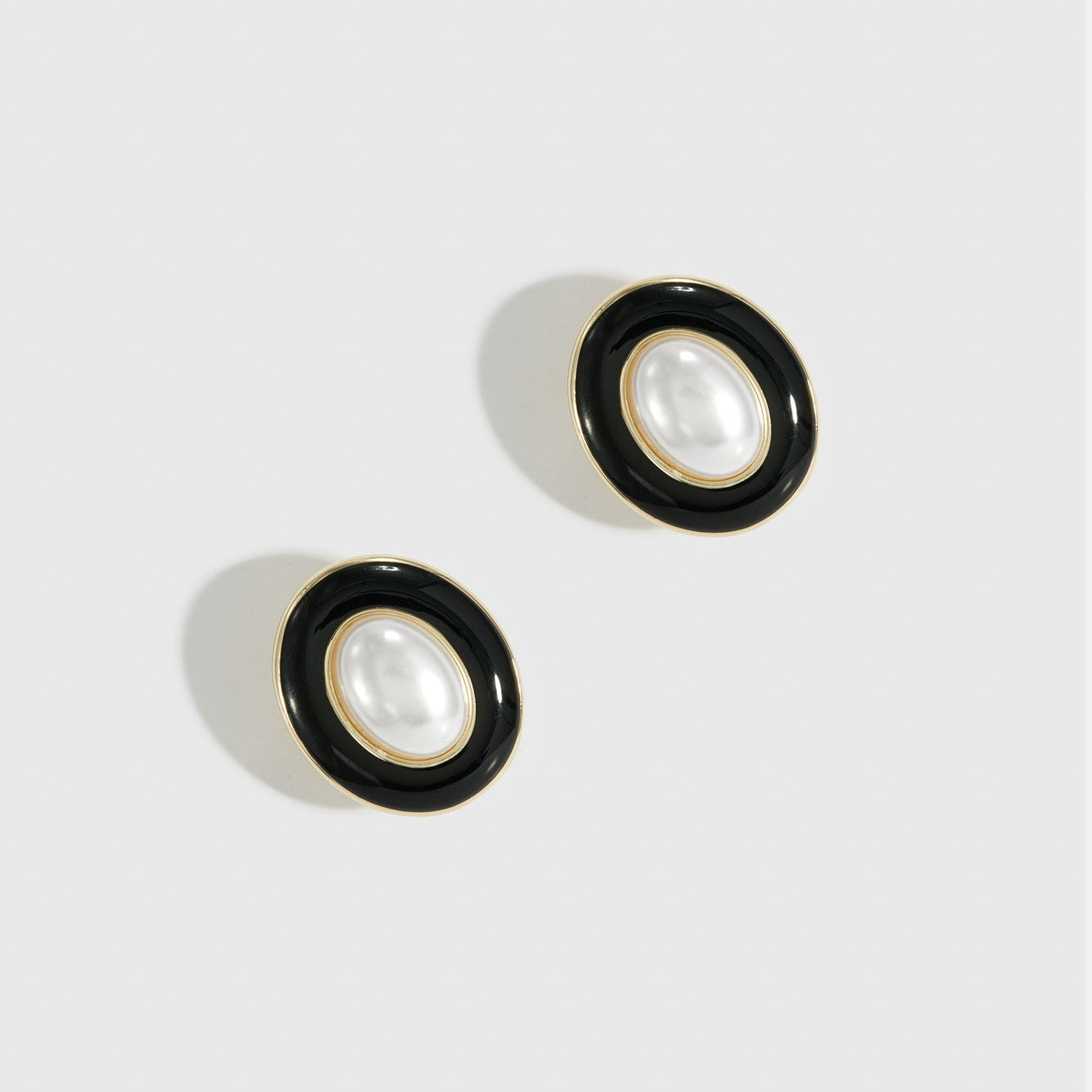 14k gold plated N.19 stud earrings with black enamel and a glass pearl, shown on a plain background.