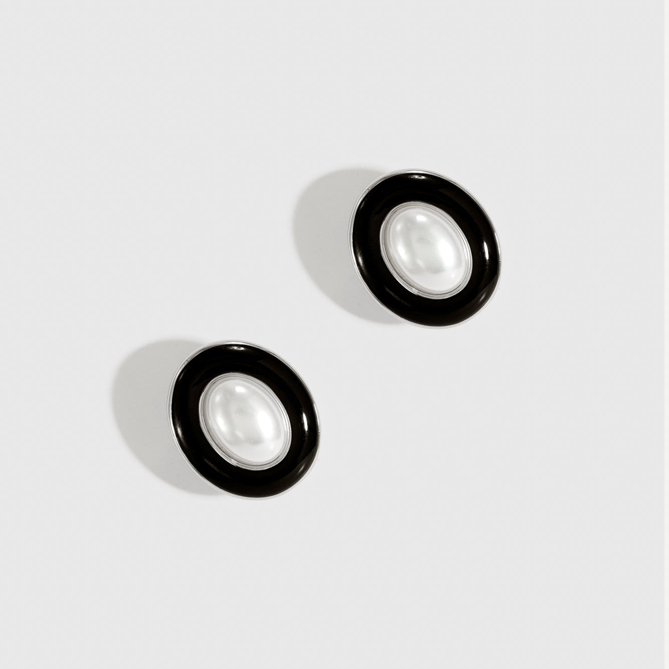 Silver plated N.19 stud earrings with black enamel and a glass pearl, shown on a plain background.
