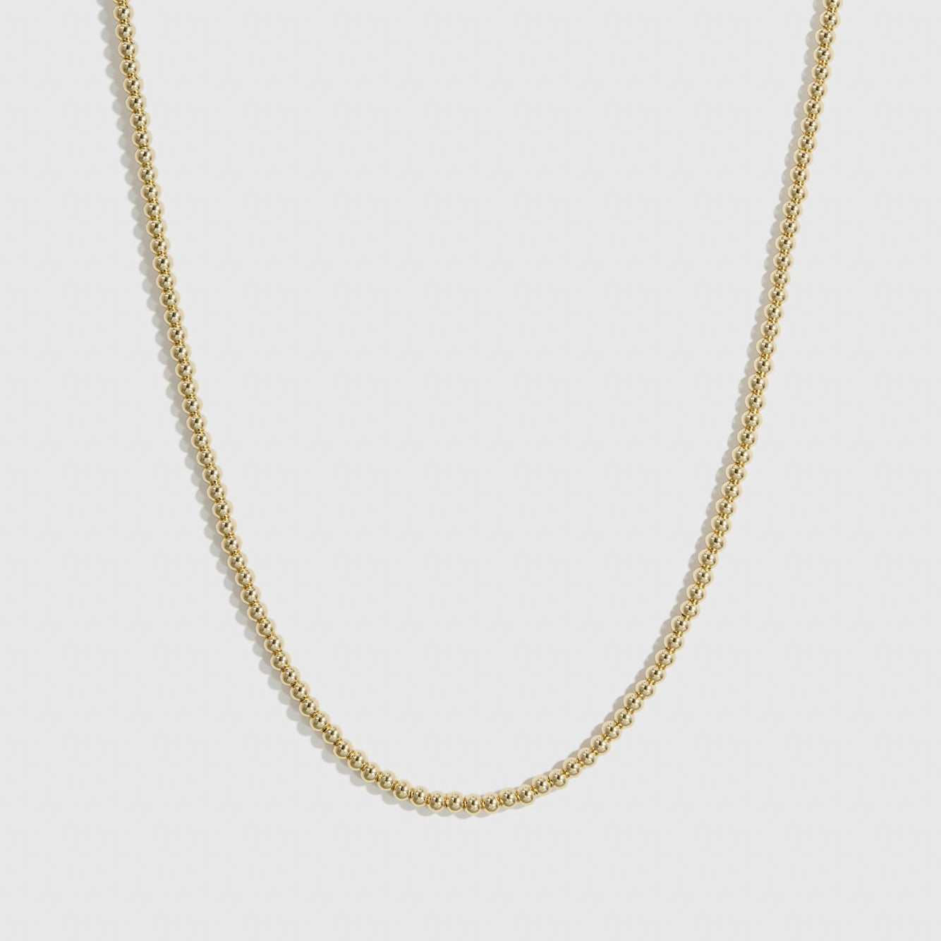 14k gold plated small beaded necklace, shown on a plain background.