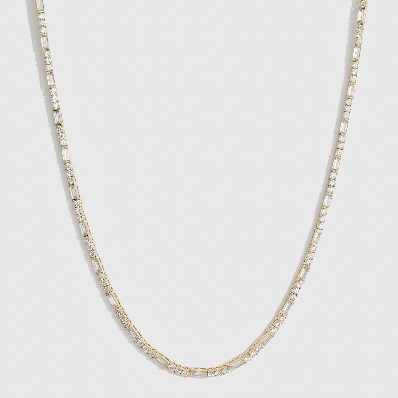 14k gold plated Amina tennis necklace with round and baguette cubic zirconia, shown on a plain background.