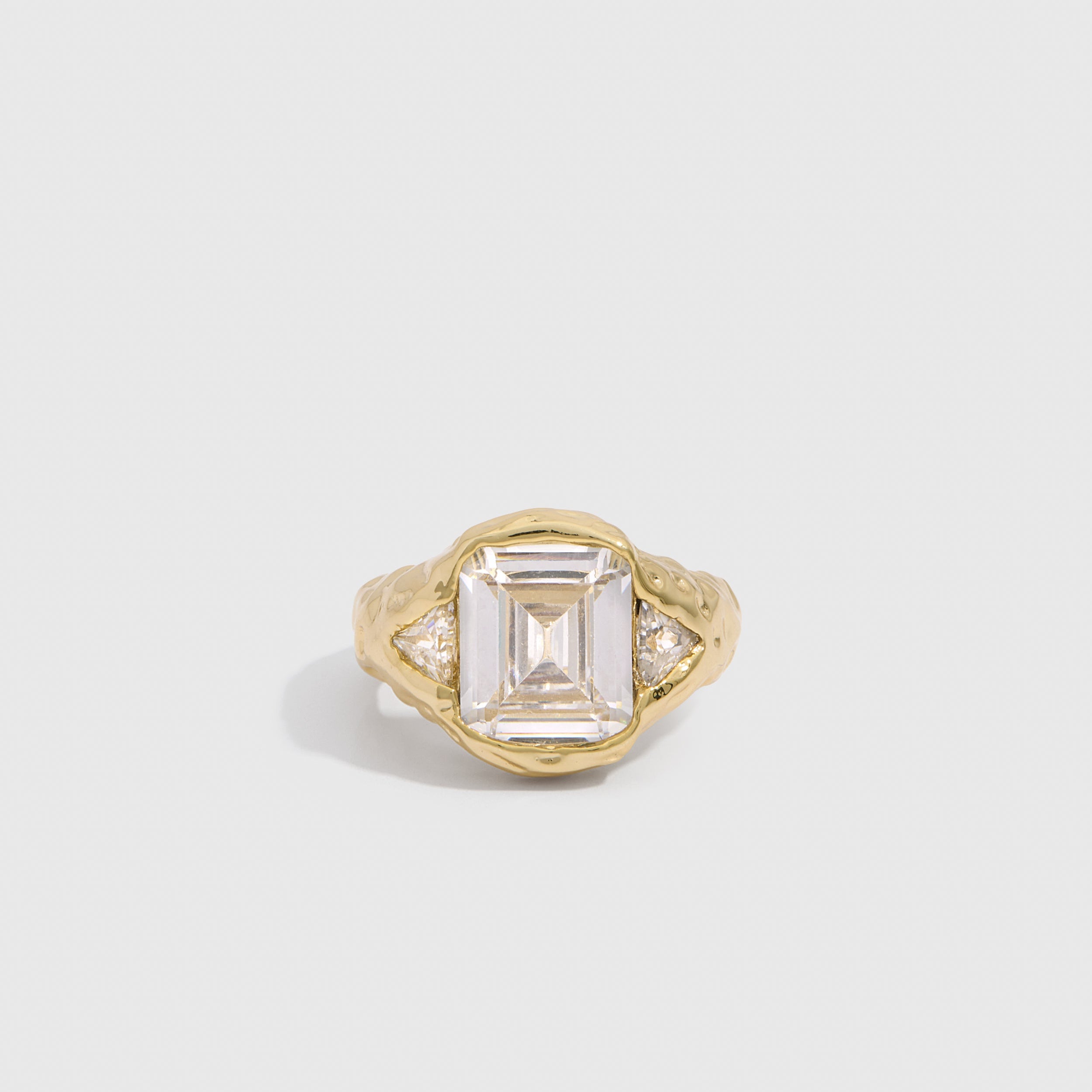 14k gold plated statement ring with emerald-cut and triangle-cut cubic zirconia on a wavy band, shown on a plain background.
