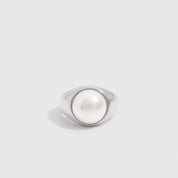 Silver dome ring with a half freshwater pearl set proud of the band, shown on a plain background.