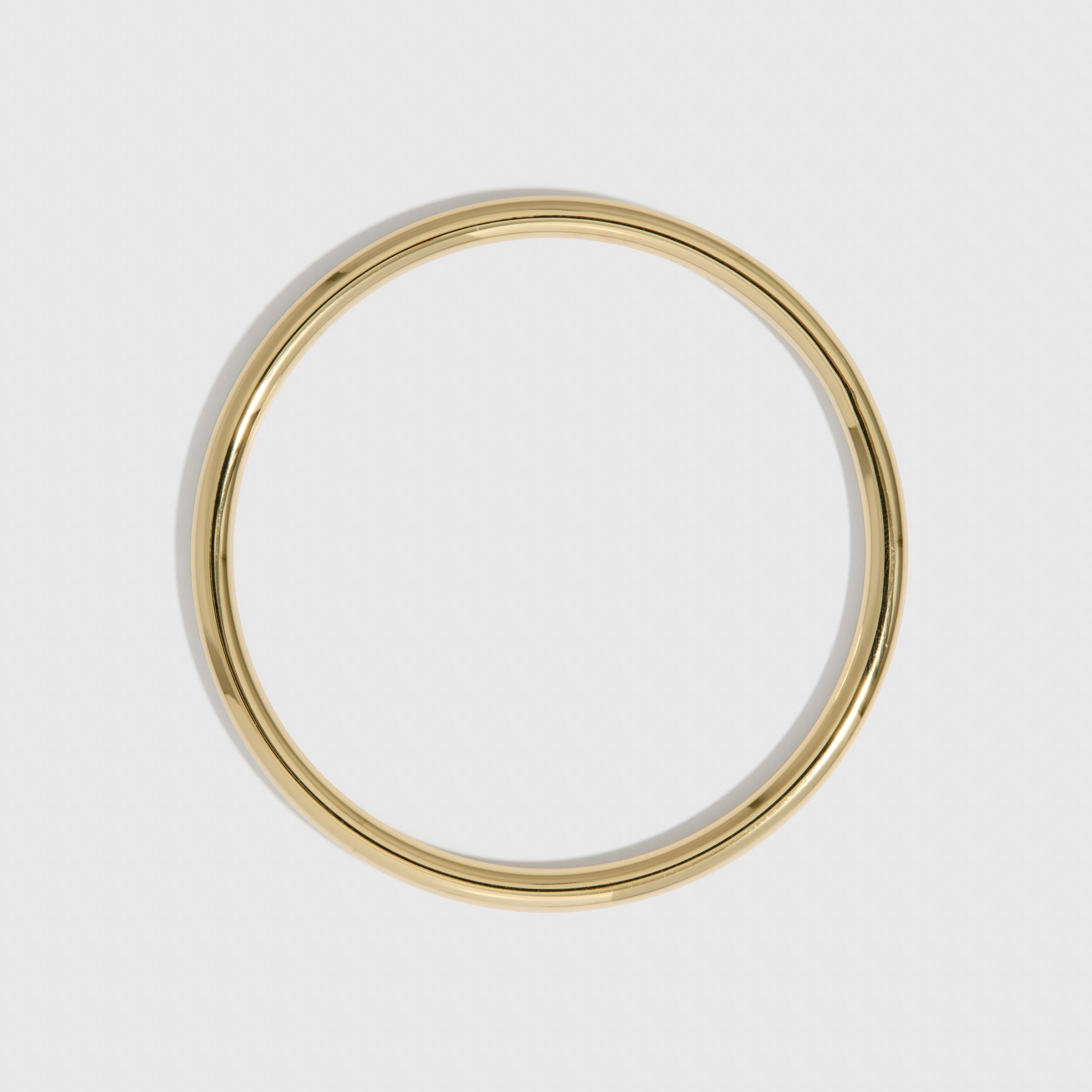 14k gold plated delicate stackable bangle bracelet shown on a plain background.
