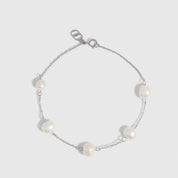 Silver bracelet with genuine freshwater pearls strung along a fine chain, shown on a plain background.