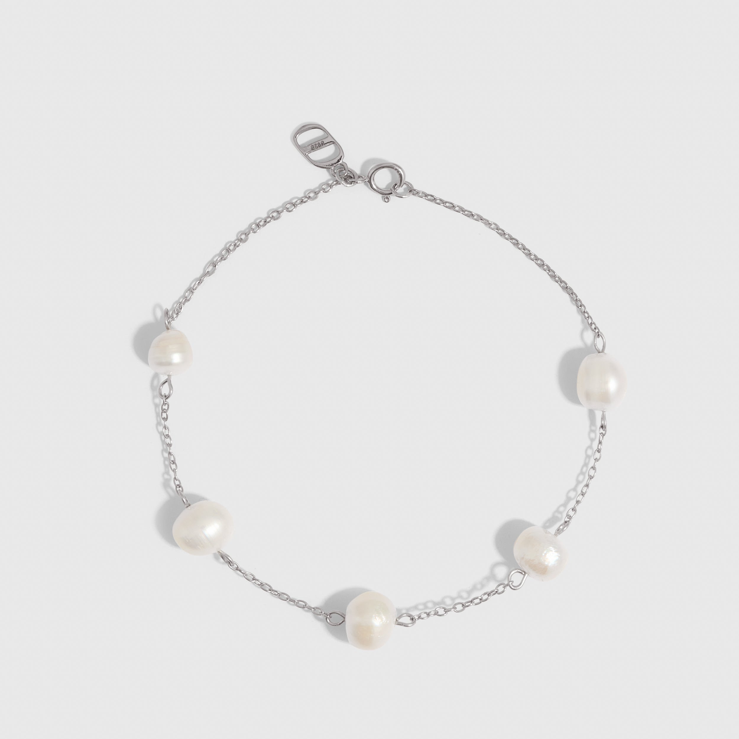 Silver bracelet with genuine freshwater pearls strung along a fine chain, shown on a plain background.