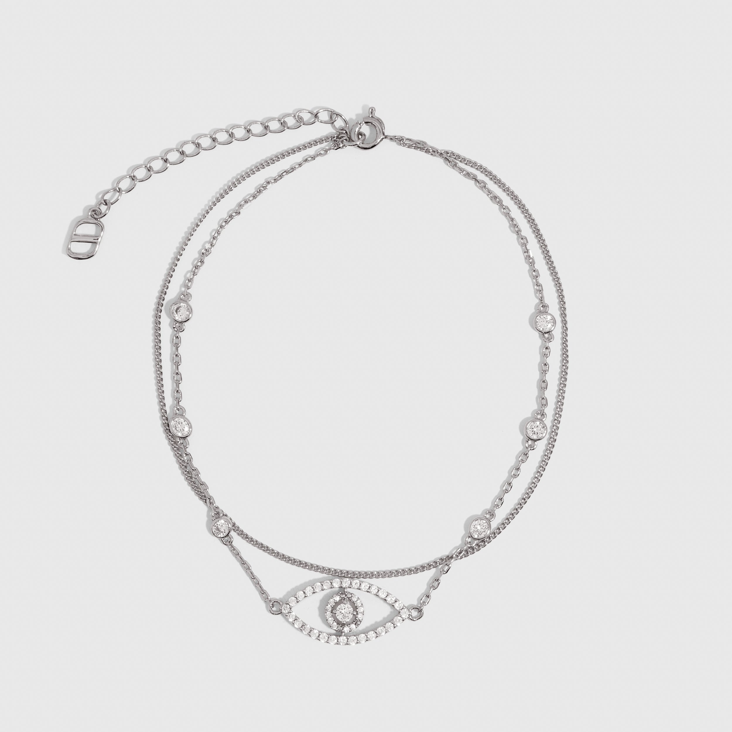 Silver anklet with an evil eye pendant and cubic zirconia pavé detailing, shown on a plain background.