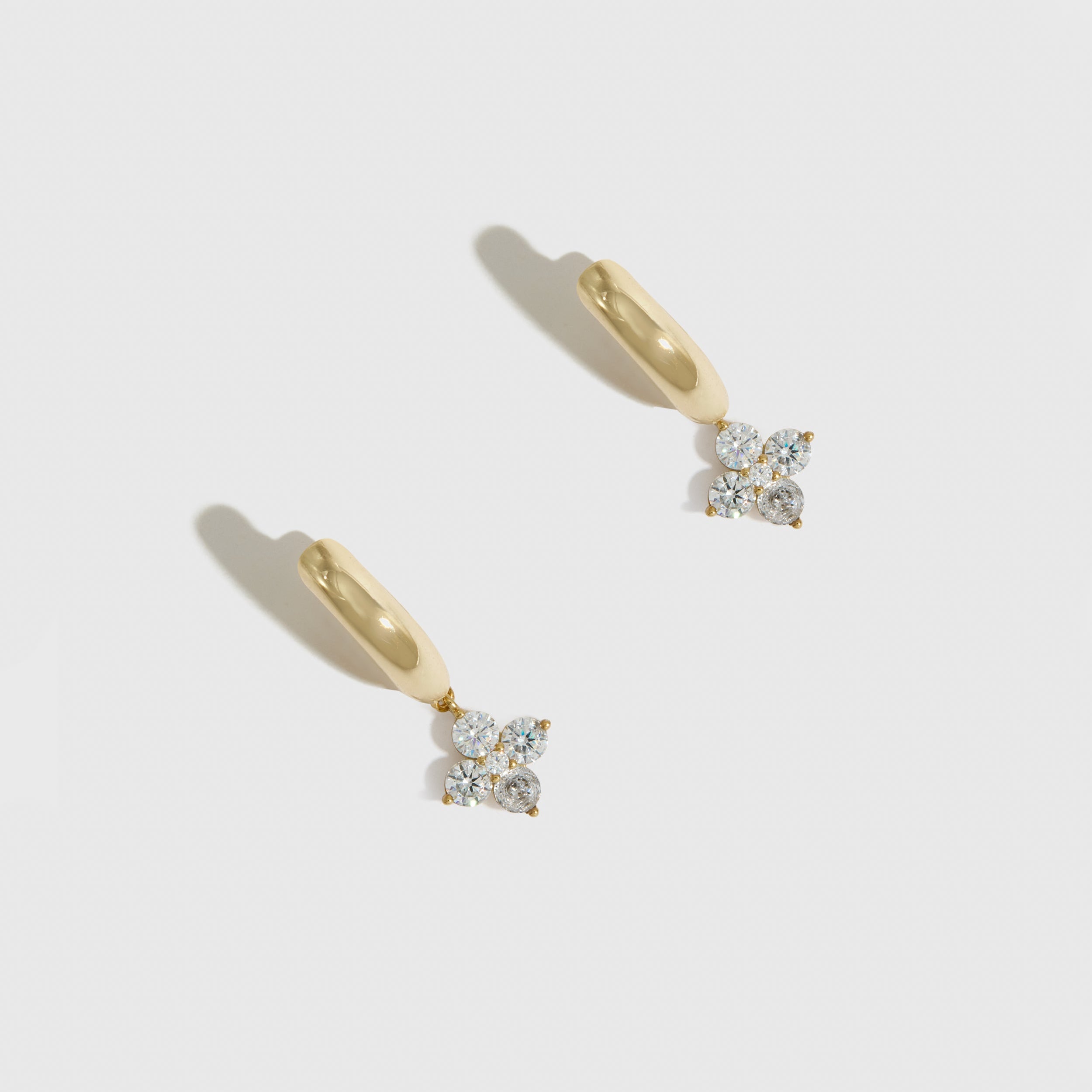 14k gold plated clover motif huggie hoop earrings with cubic zirconia detailing, shown on a plain background.
