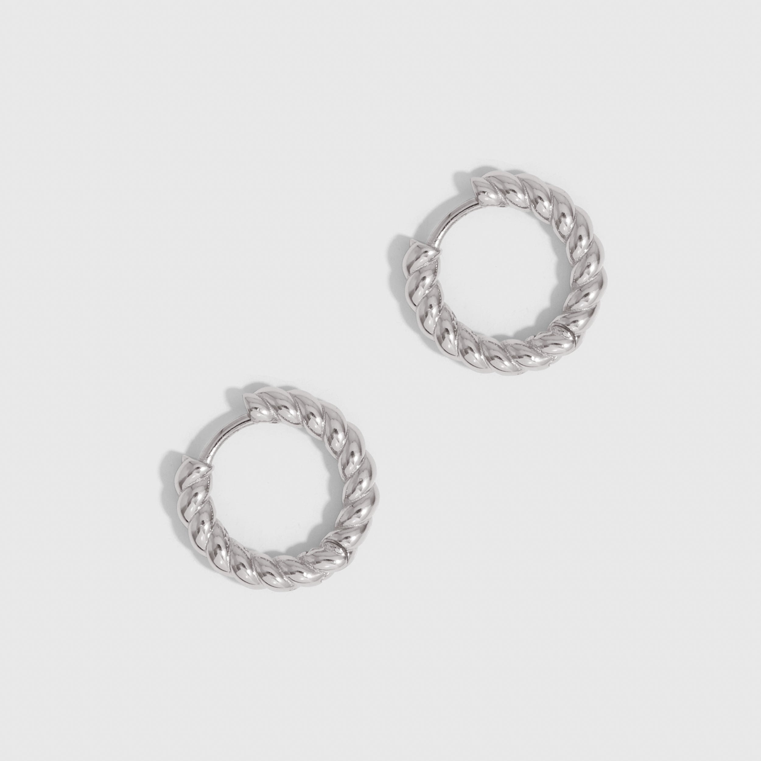 Silver braided texture huggie hoop earrings, shown on a plain background.