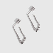 Silver organic-shaped drop hoop earrings shown on a plain background, highlighting their fluid silhouette.