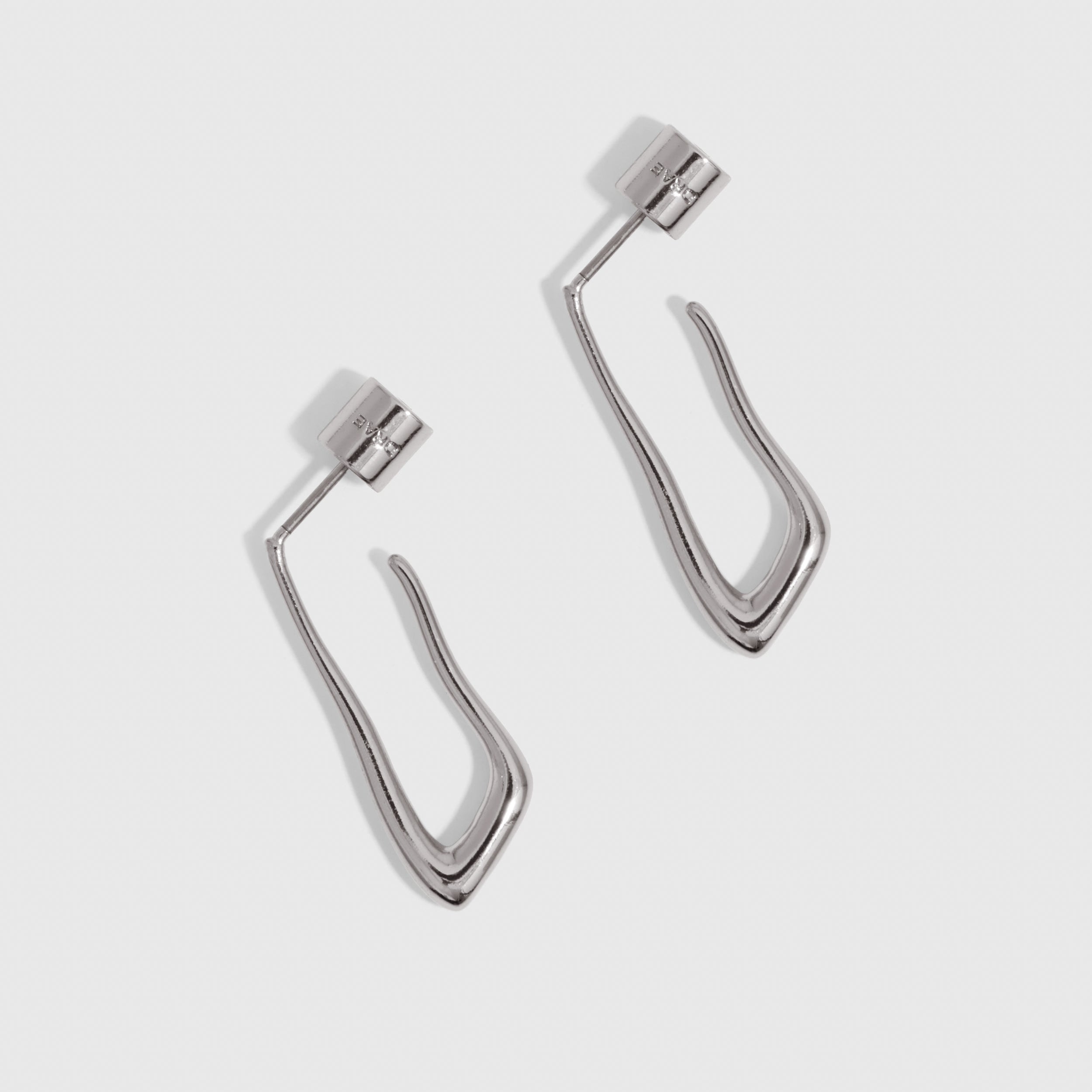 Silver organic-shaped drop hoop earrings shown on a plain background, highlighting their fluid silhouette.