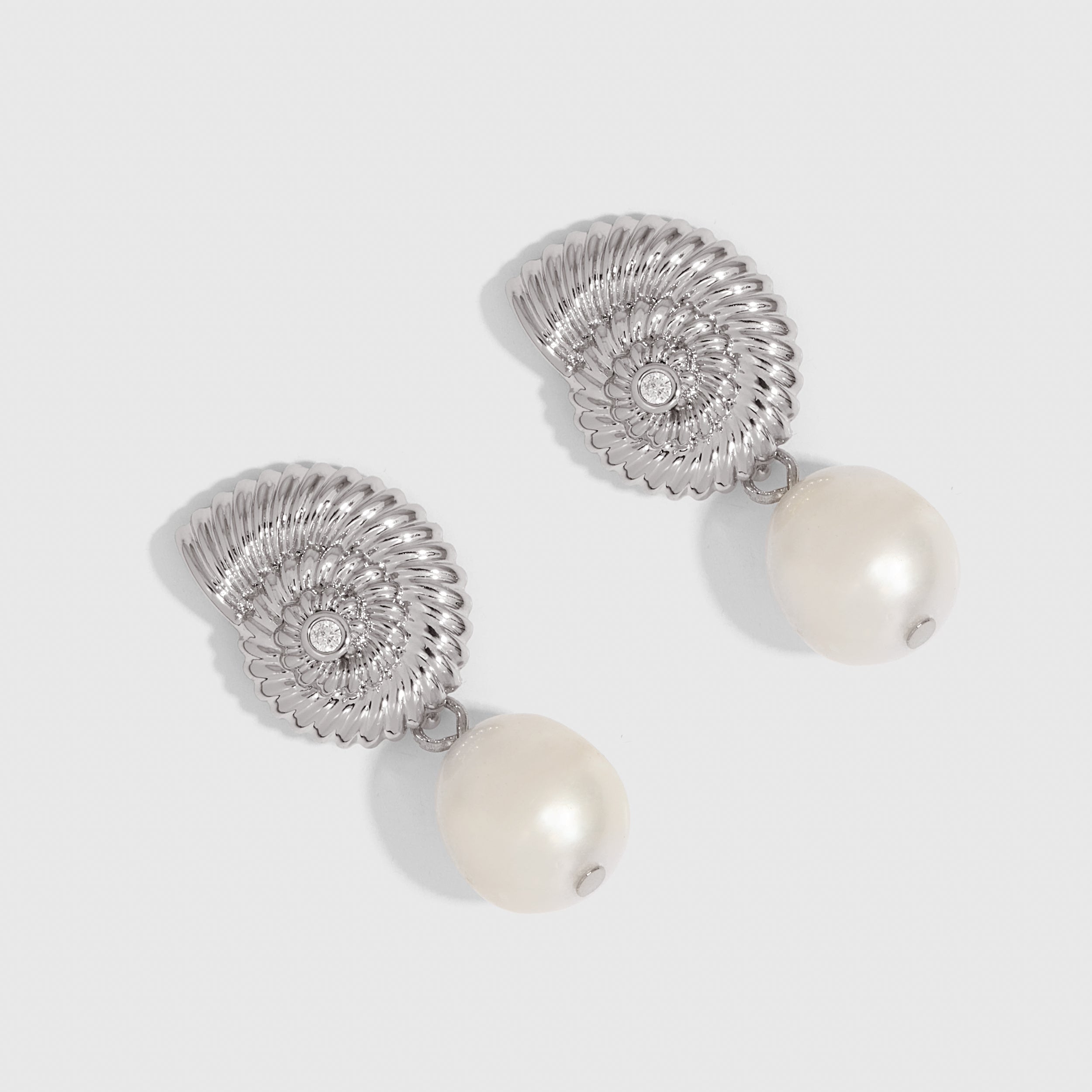 Silver seashell stud earrings cradling a genuine freshwater pearl, shown on a plain background.