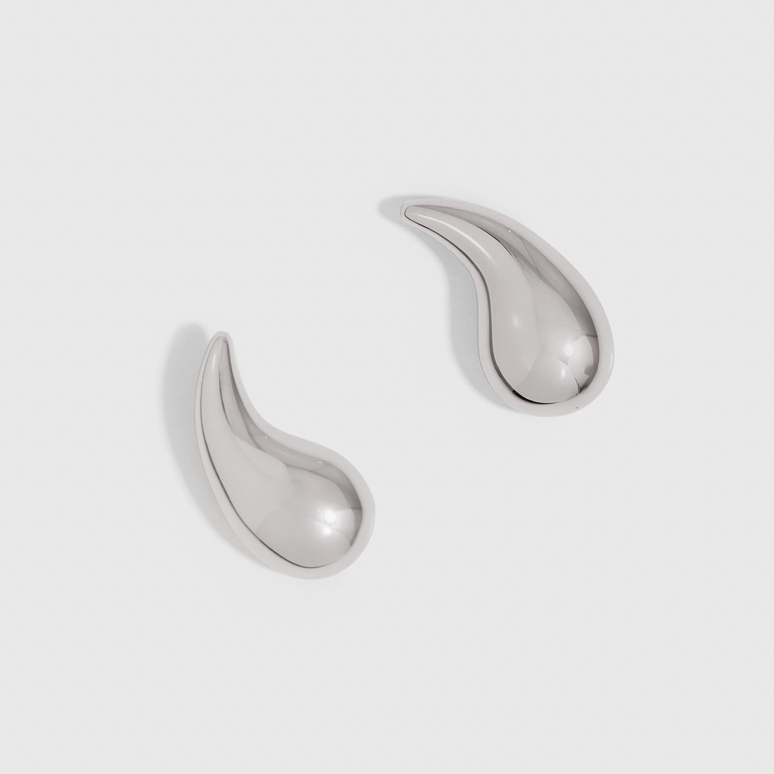 Silver sculptural water-drop shaped stud earrings, shown on a plain background.
