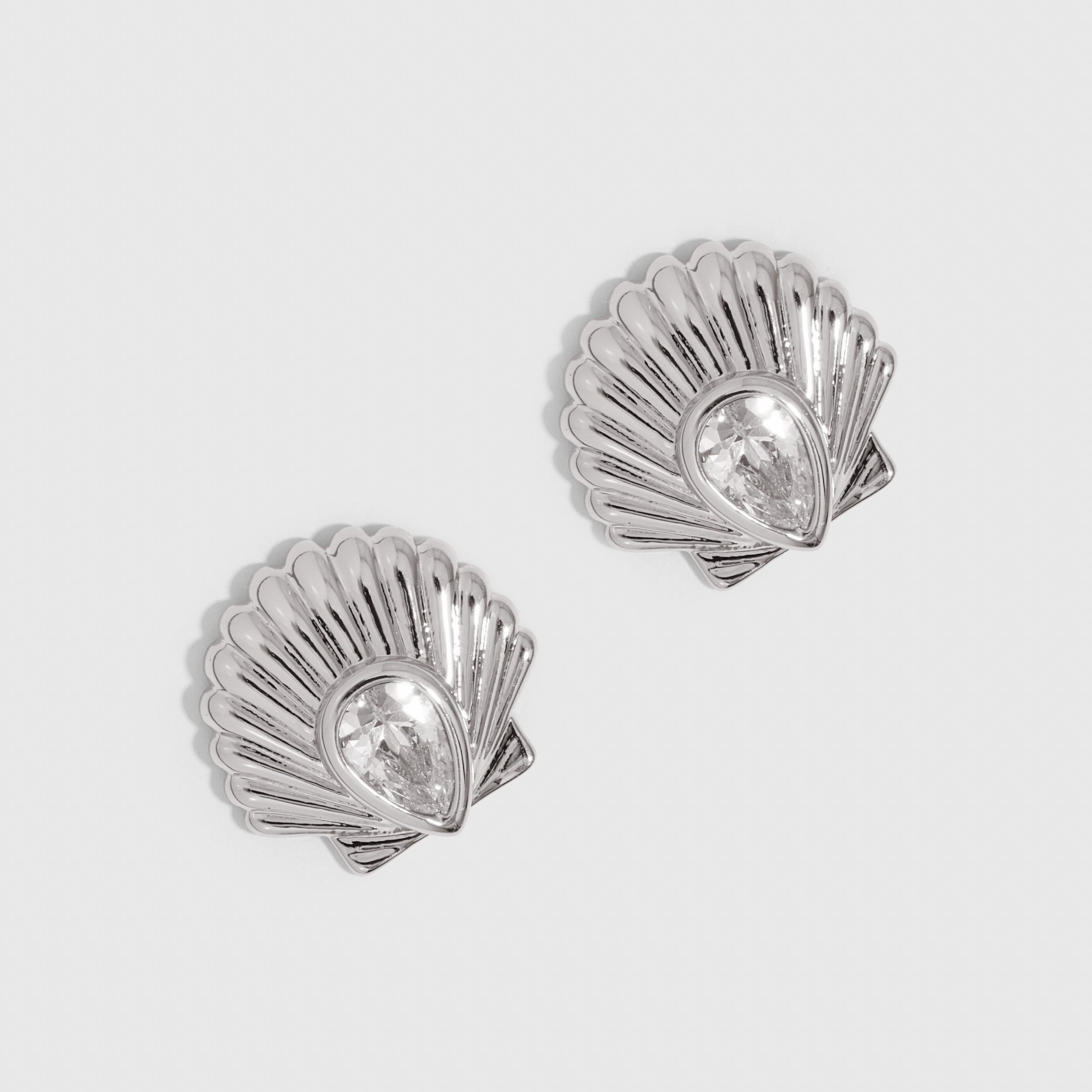 Silver seashell stud earrings with a teardrop-cut cubic zirconia, shown on a plain background.