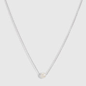 Silver solitaire pendant necklace with one round freshwater pearl on a fine cable chain, shown on a plain background.