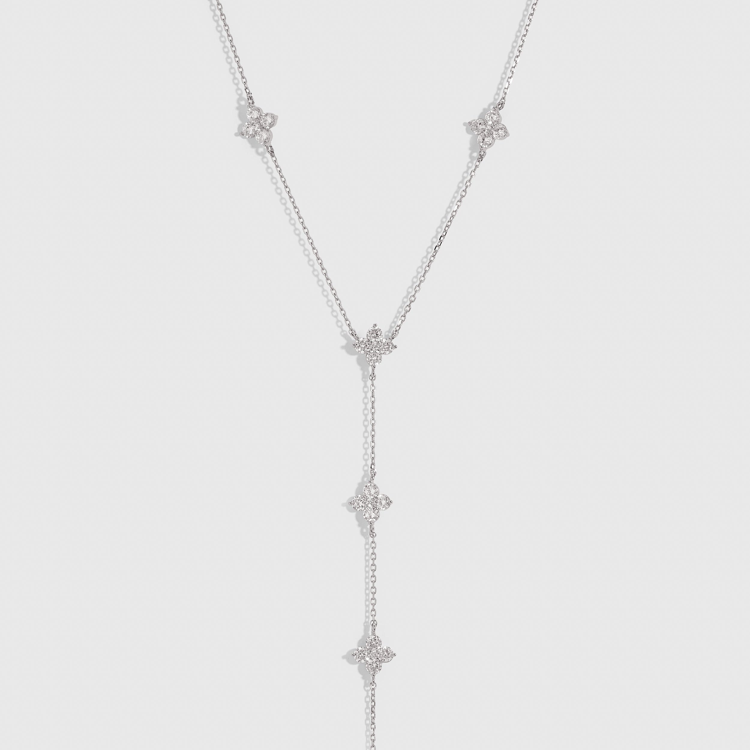 Silver multi-clover lariat necklace with cubic zirconia detailing and a draped chain, shown on a plain background.