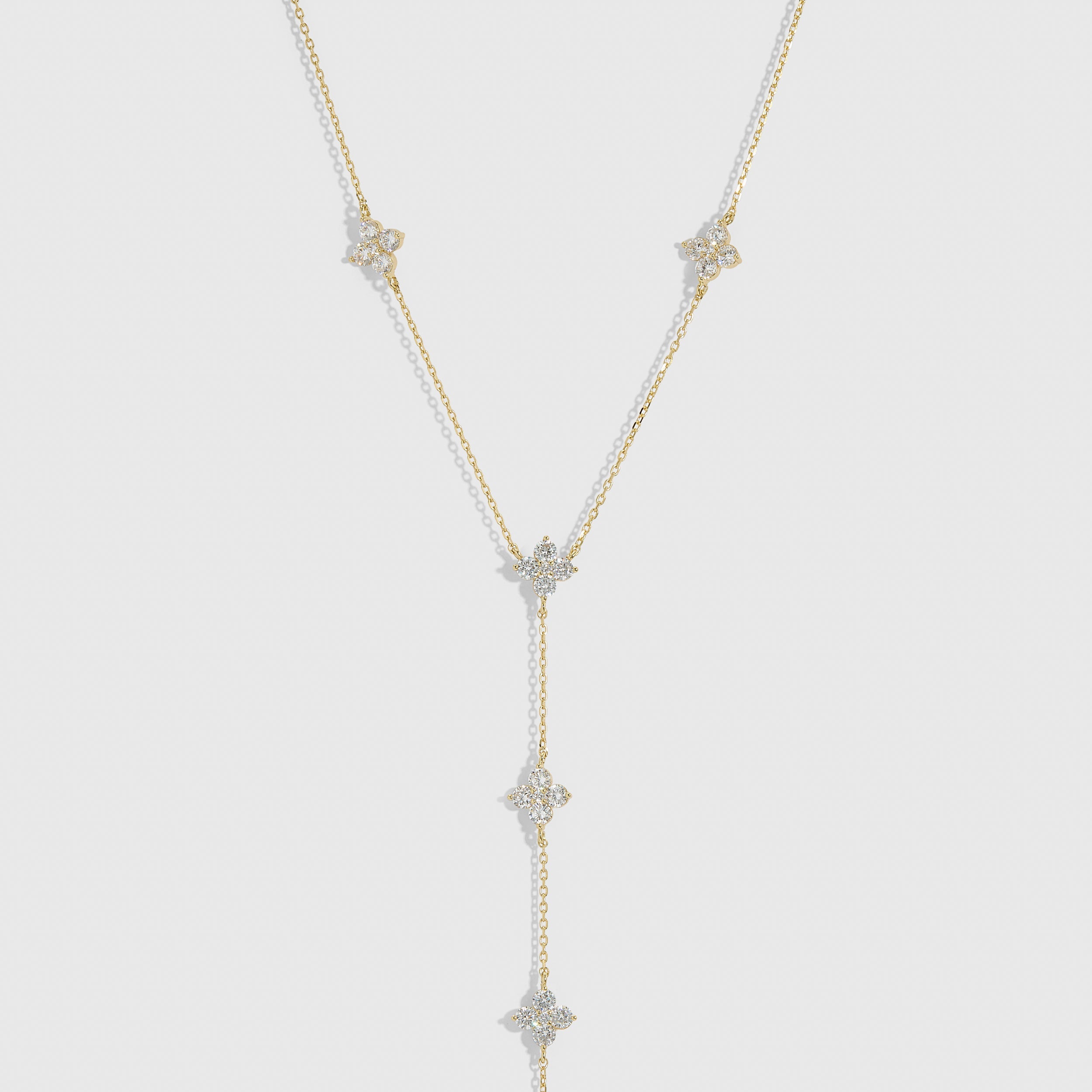 14k gold plated multi-clover lariat necklace with cubic zirconia detailing and a draped chain, shown on a plain background.