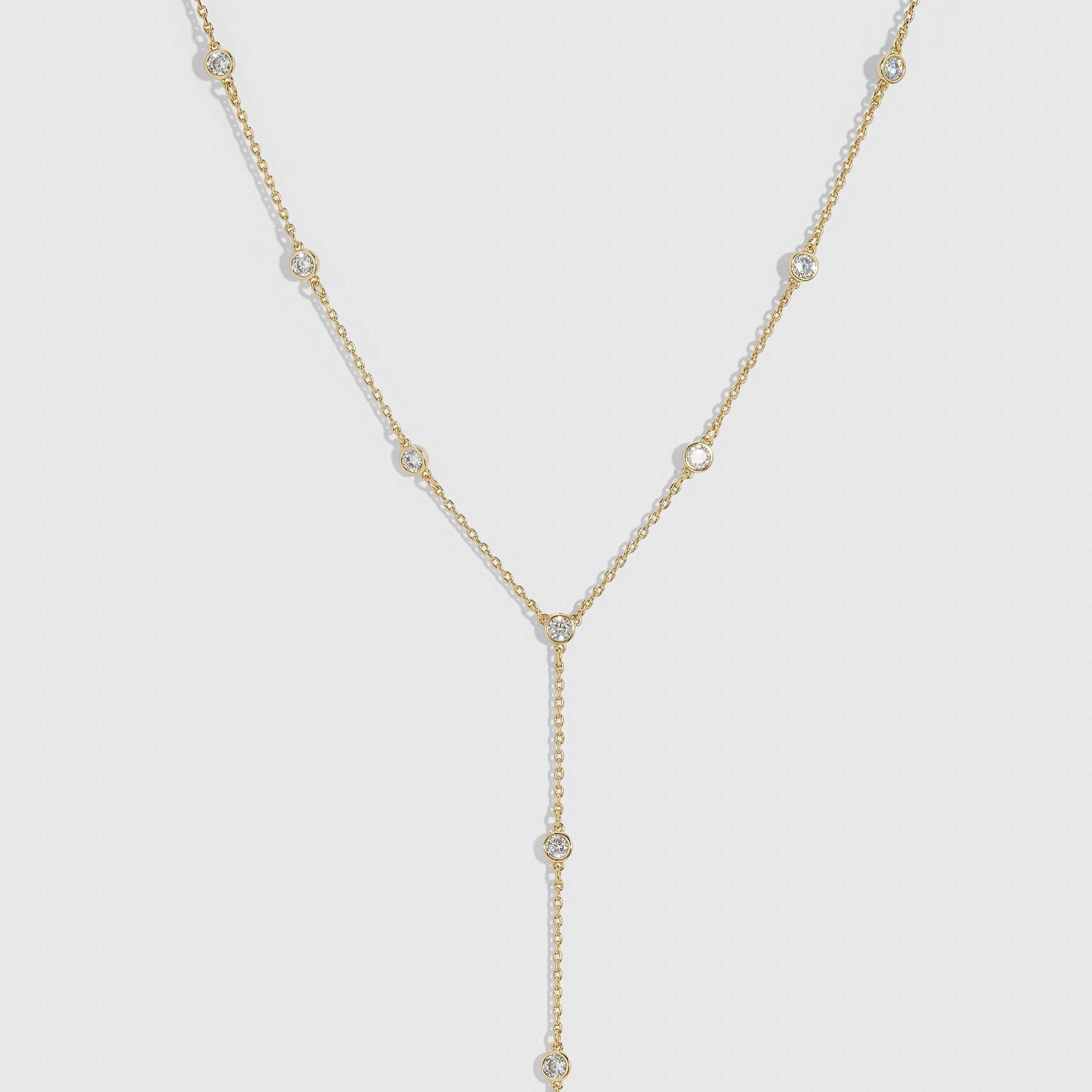 14k gold plated bezel-set cubic zirconia lariat necklace with a draped adjustable chain, shown on a plain background.