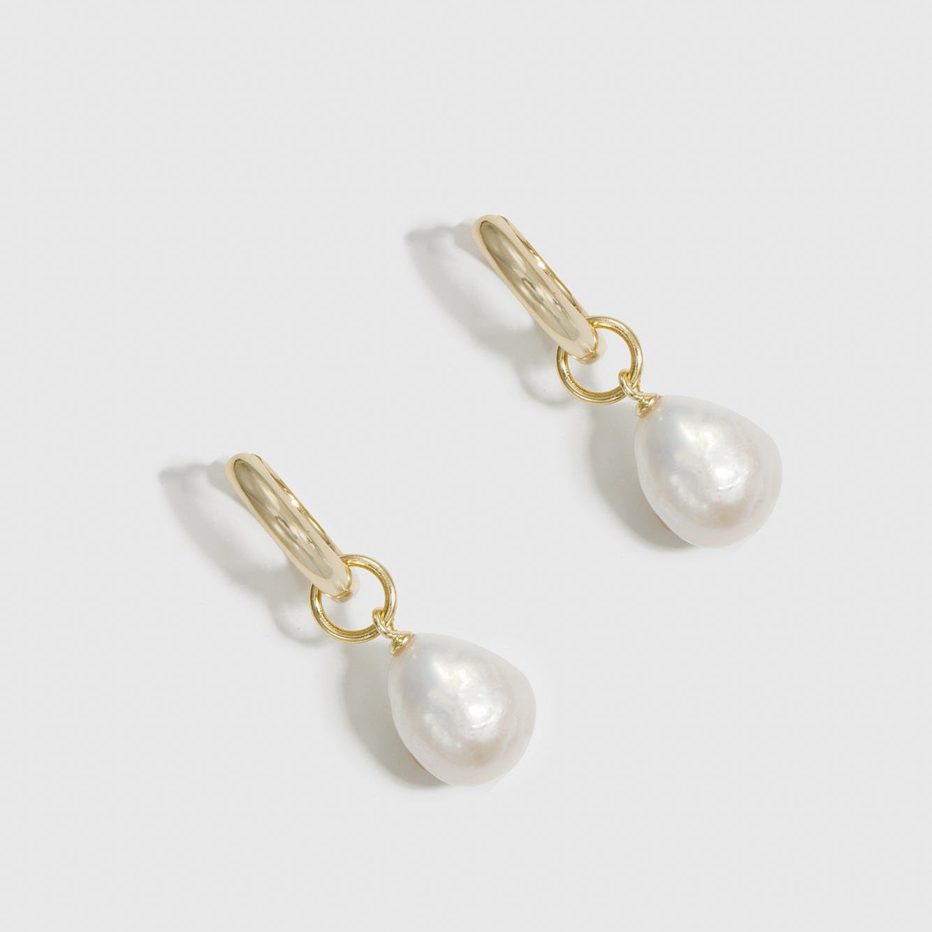 14k gold plated sterling silver 925 baroque pearl huggie earrings with baroque pearls, shown on a plain background.