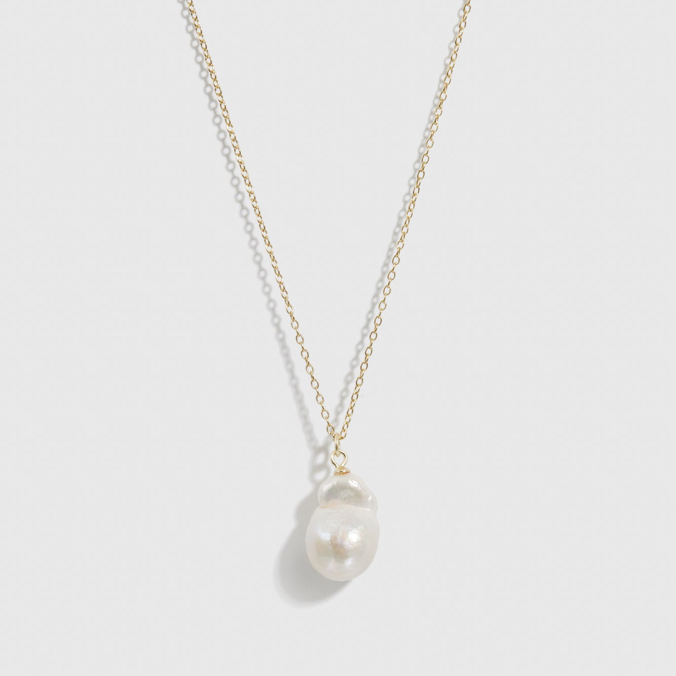 14k gold plated sterling silver 925 solitaire baroque pearl necklace with a baroque pearl, shown on a plain background.