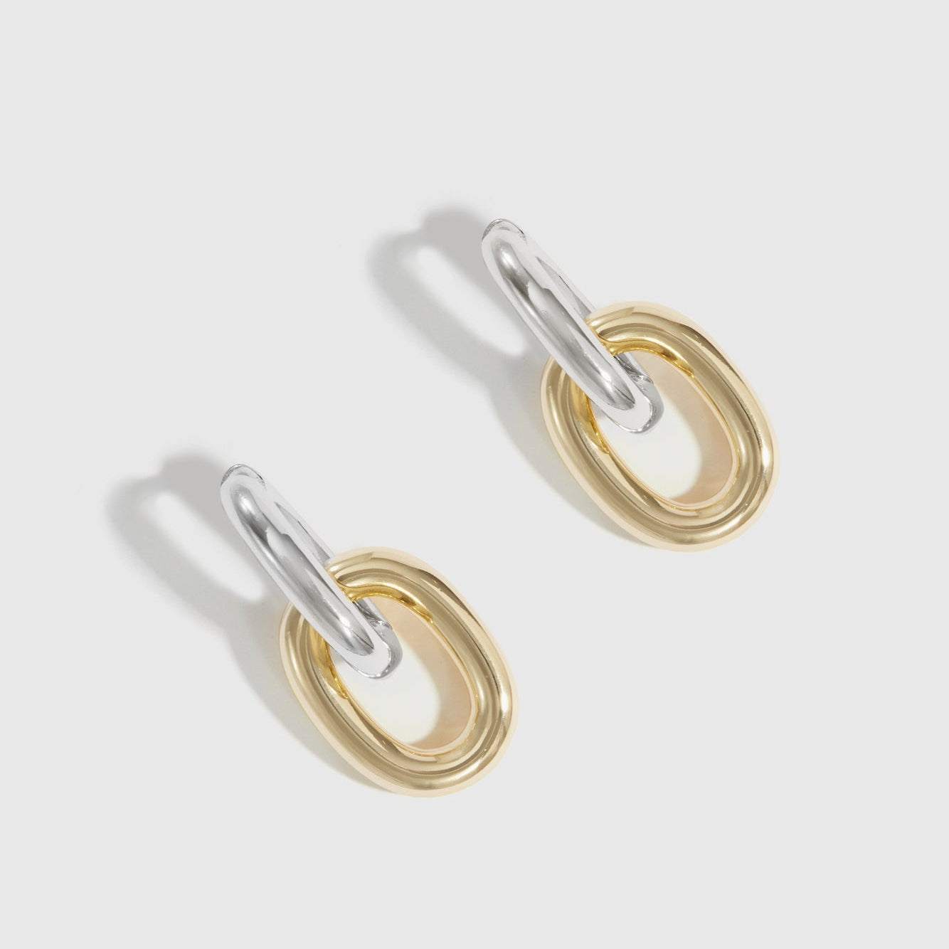 Mixed metal oval link bare pendant hoops, shown on a plain background.