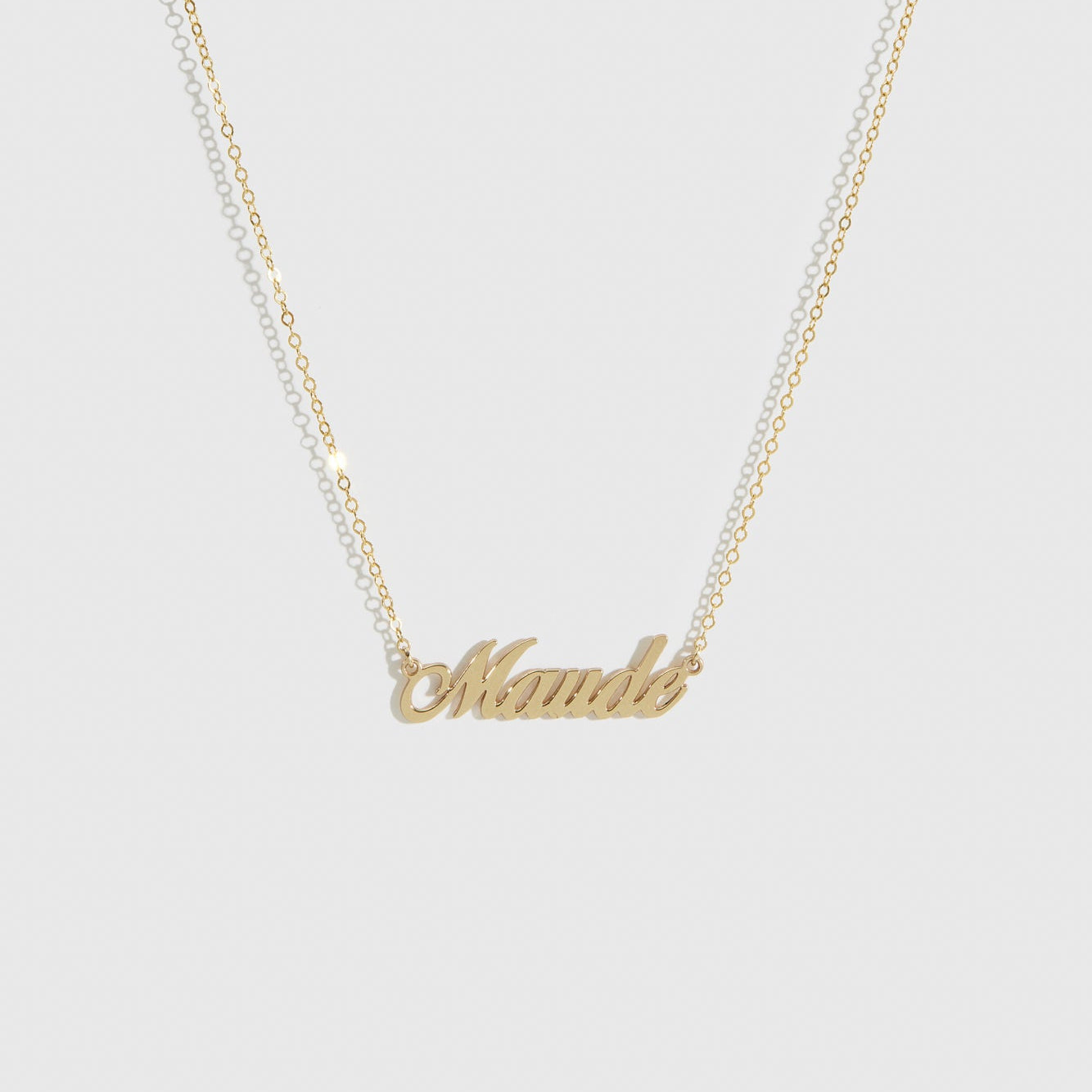 14k solid gold personalized cursive font nameplate necklace, shown on a plain background.