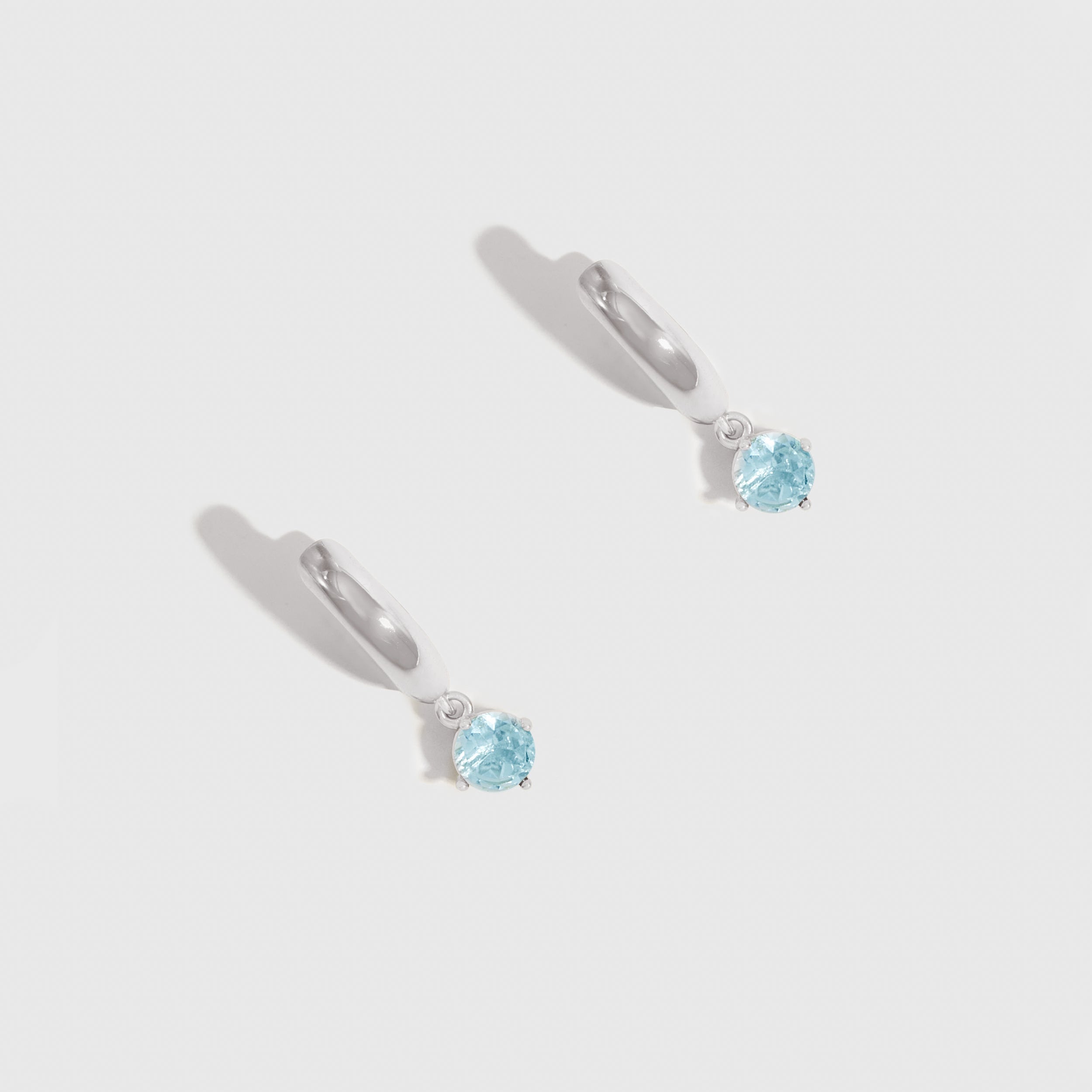 Pair of silver earrings with blue gemstones on a light gray background