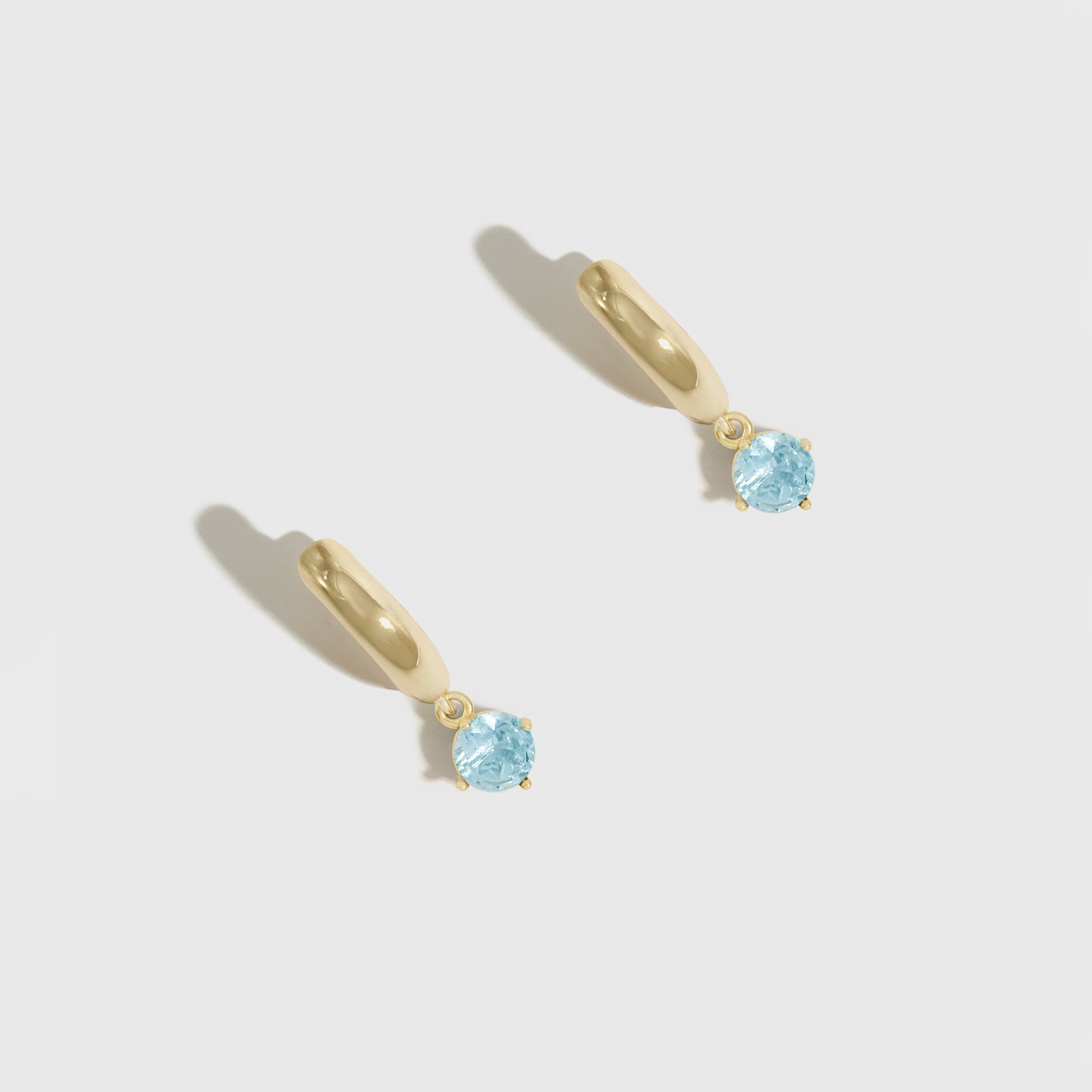 Pair of silver earrings with blue gemstones on a light gray background