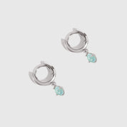 Pair of silver hoop earrings with turquoise stones on a light gray background