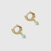 Gold hoop earrings with turquoise stones on a light gray background