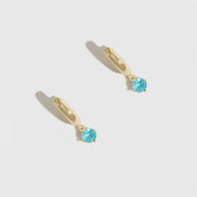 Gold earrings with blue gemstones on a light gray background