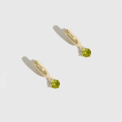 Gold earrings with green gemstones on a white background
