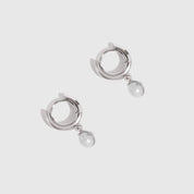 Pair of silver hoop earrings with pearl drops on a light gray background