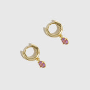 Gold hoop earrings with pink gemstones on a light gray background