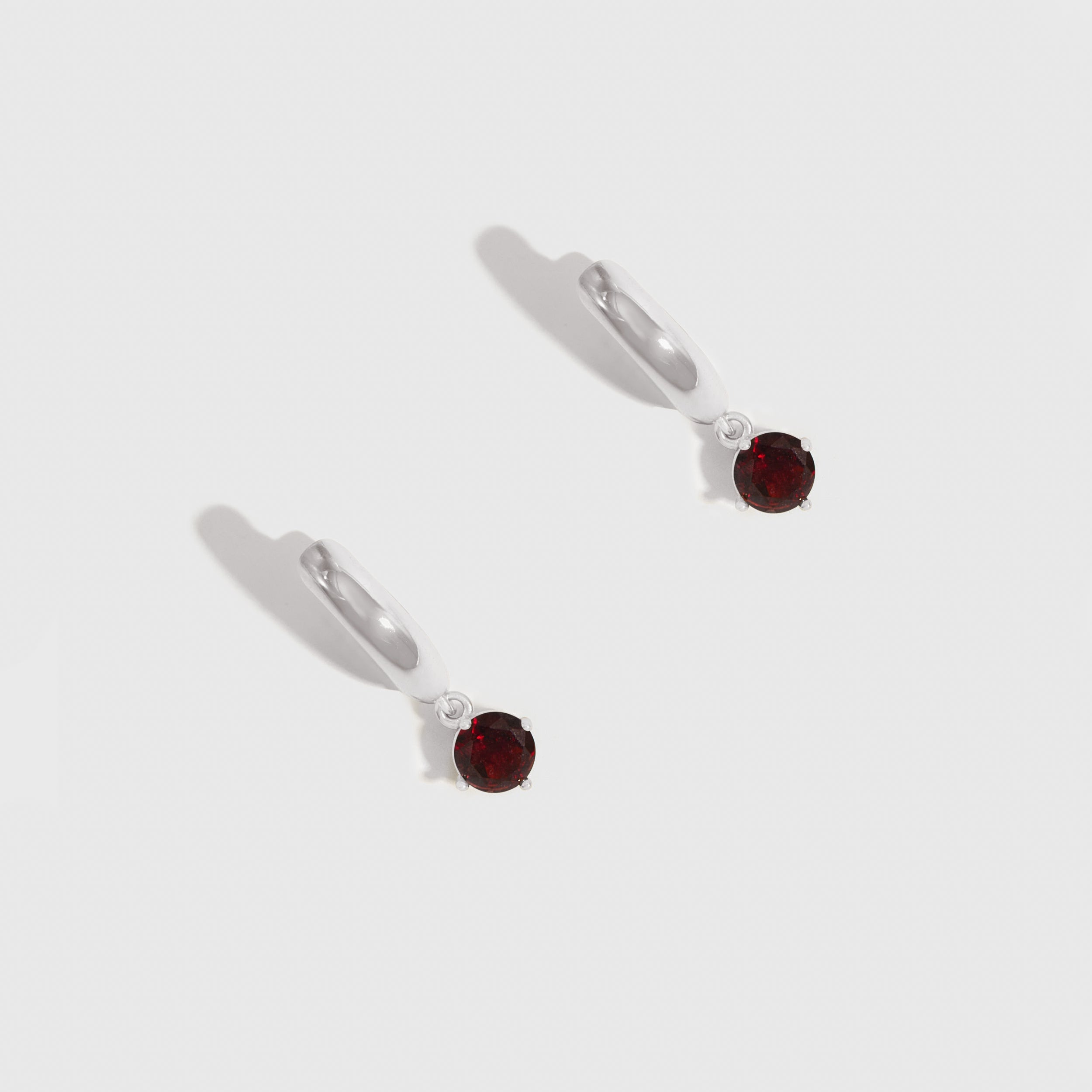 Pair of earrings with red gemstones on a white background
