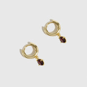 Gold hoop earrings with red gemstones on a white background