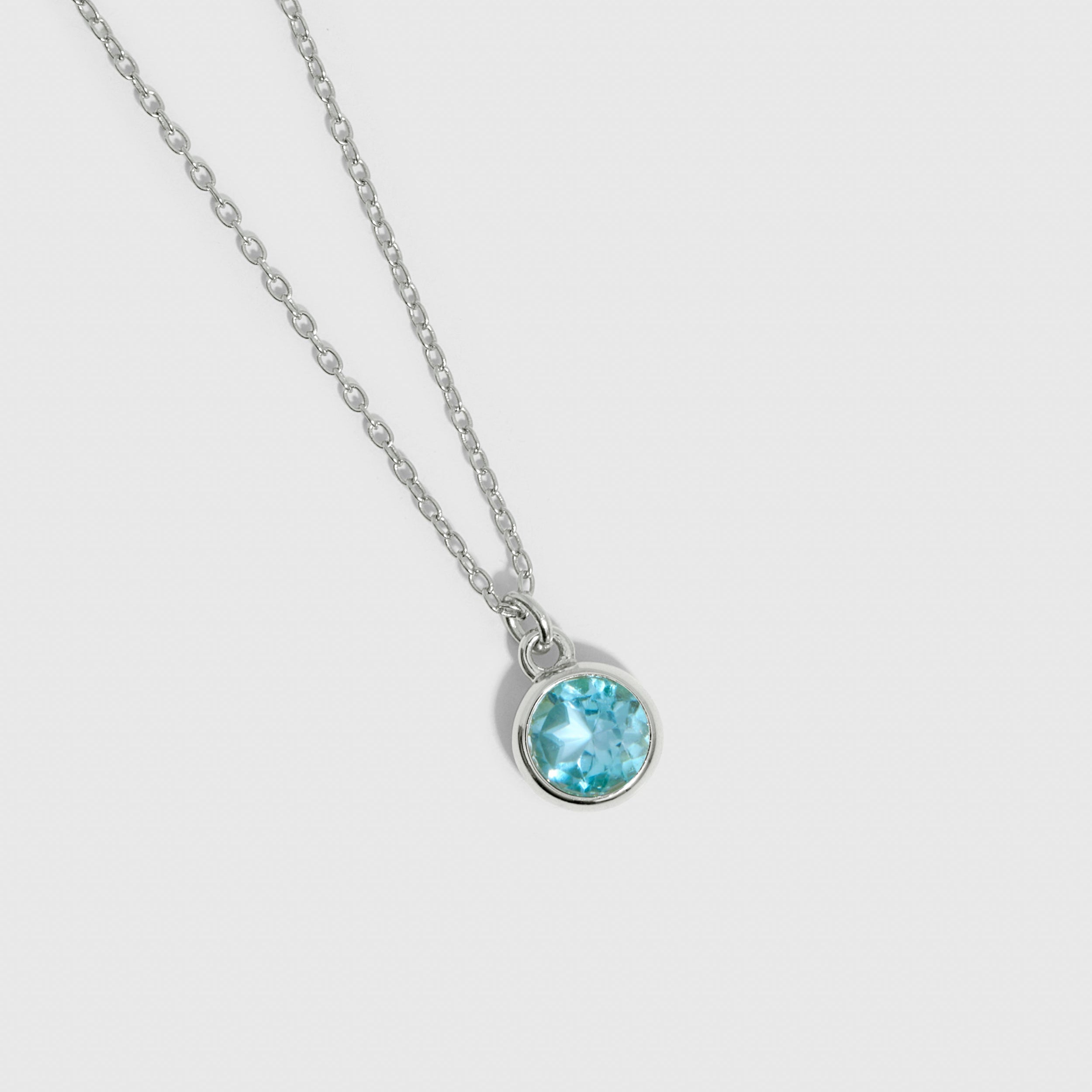 Necklace with a blue gemstone pendant on a light gray background