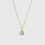 Gold necklace with a blue gemstone pendant on a light gray background