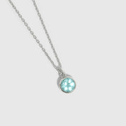 Necklace with a round pendant featuring a blue gemstone on a light gray background