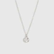 Silver necklace with a small round pendant on a light gray background